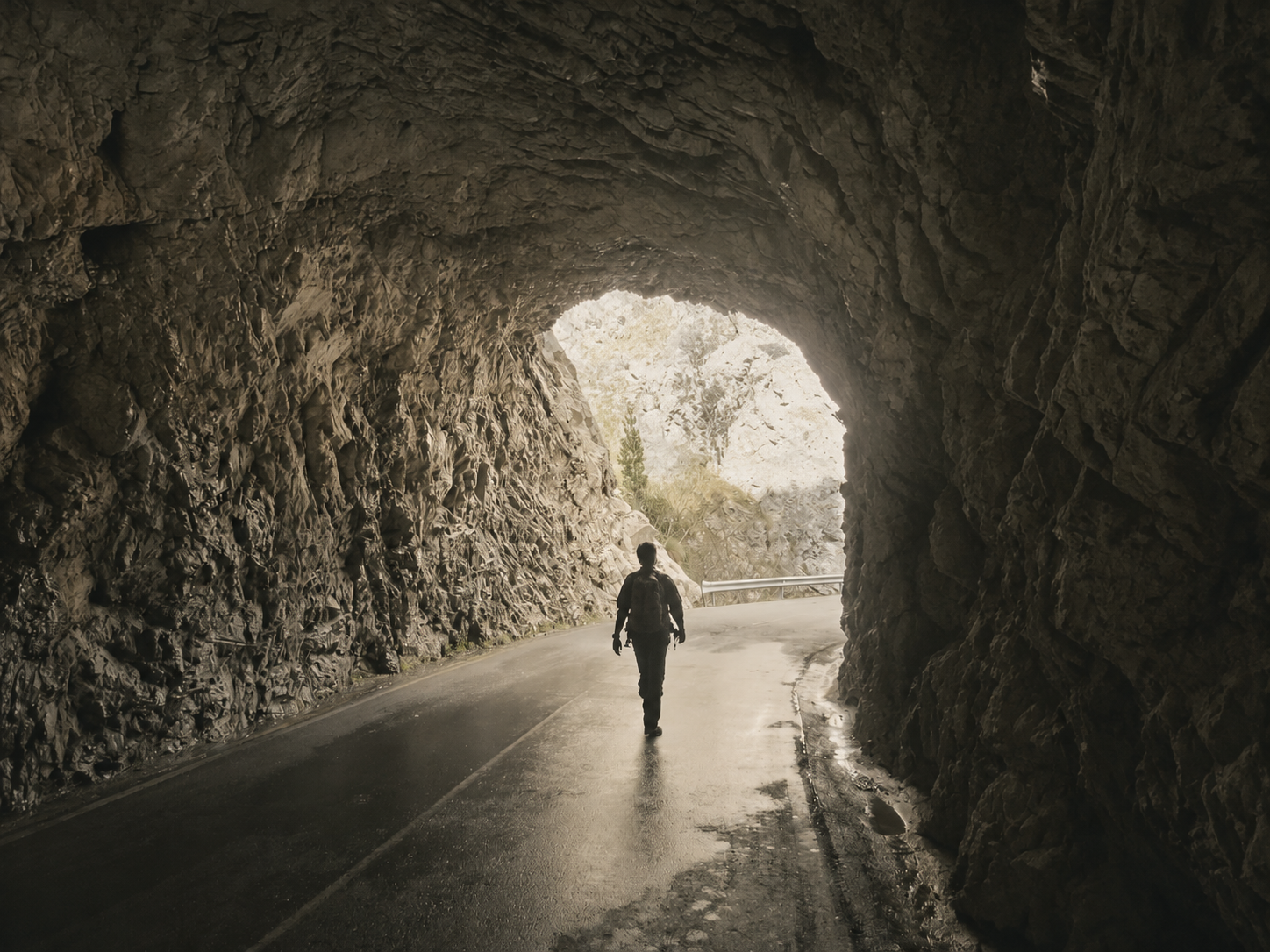 Silueta de una persona caminando hacia la luz al final de un túnel oscuro